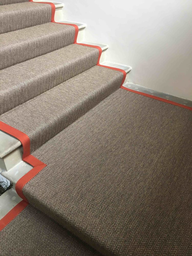 Herringbone stair runner with a contrasting red cotton border, close crop