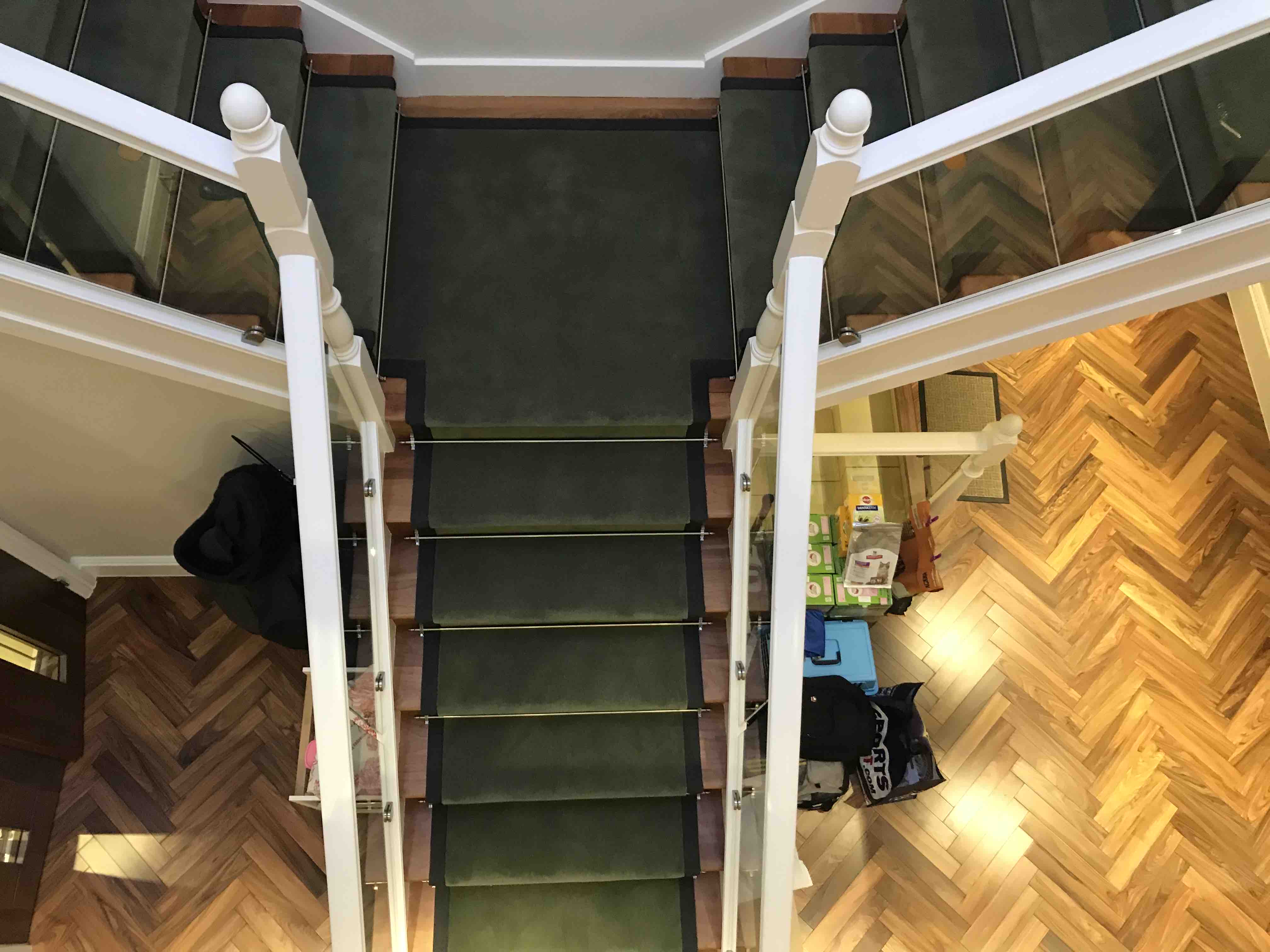 Dark green stair runner on a modern glass-balustrade staircase, Brixton